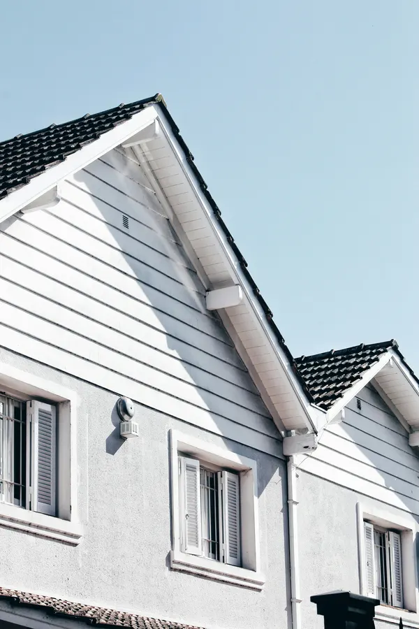 White gable end beside a freshly shingled roof