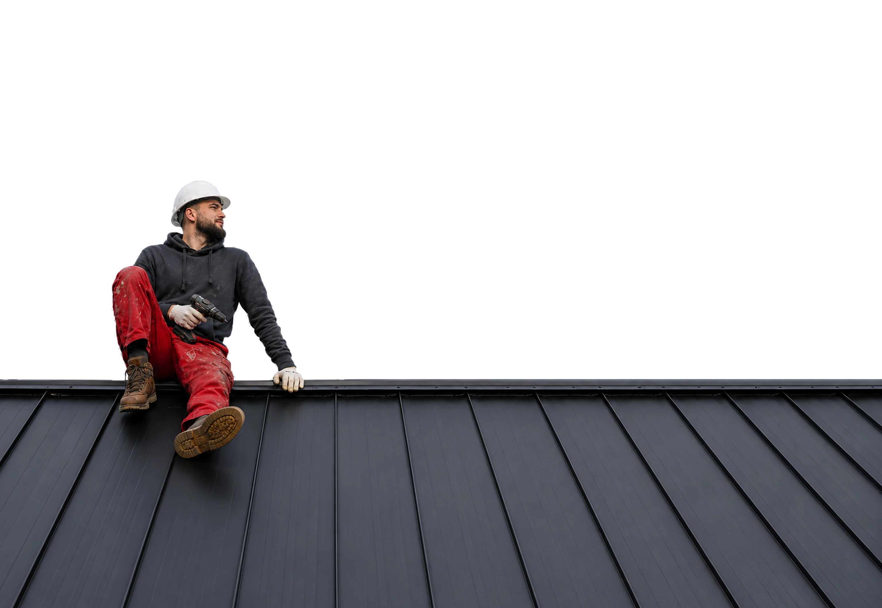 Roofing contractor sitting on a standing-seam metal roof holding a cordless drill